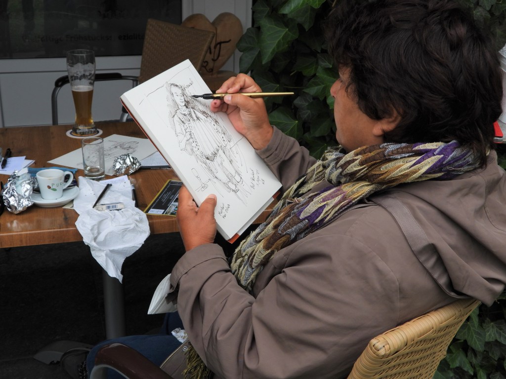 Künstlerin Nadia Baumgart beim zeichnen im Café
