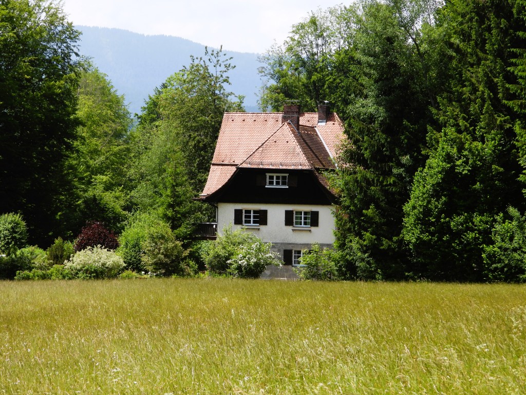 Ein traditionelles Landhaus inmitten von Bäumen und Wiese im Nationalpark Bayerischer Wald.