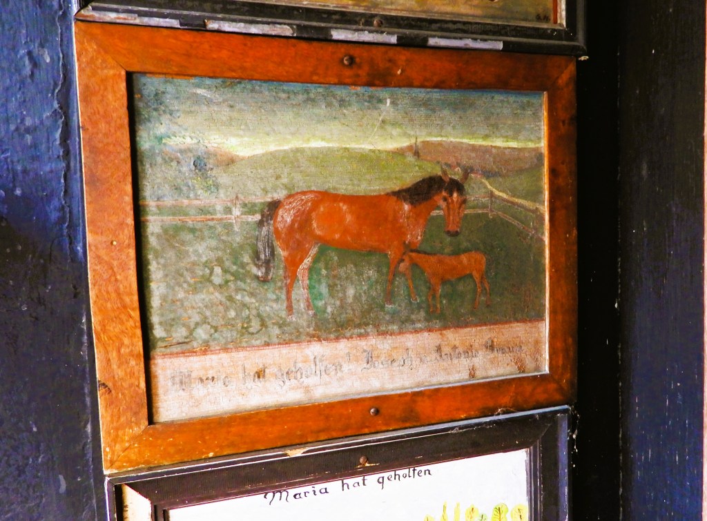 Ein Votivbild eines Pferdes mit einem Fohlen, gerahmt und an einer Wand hängend.