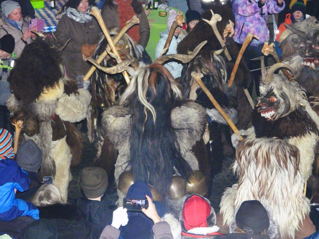 Gruppe von Perchten mit kunstvoll geschnitzten Masken und Stäben während des Perchtenlufs in Bad Birnbach, umgeben von Zuschauern.