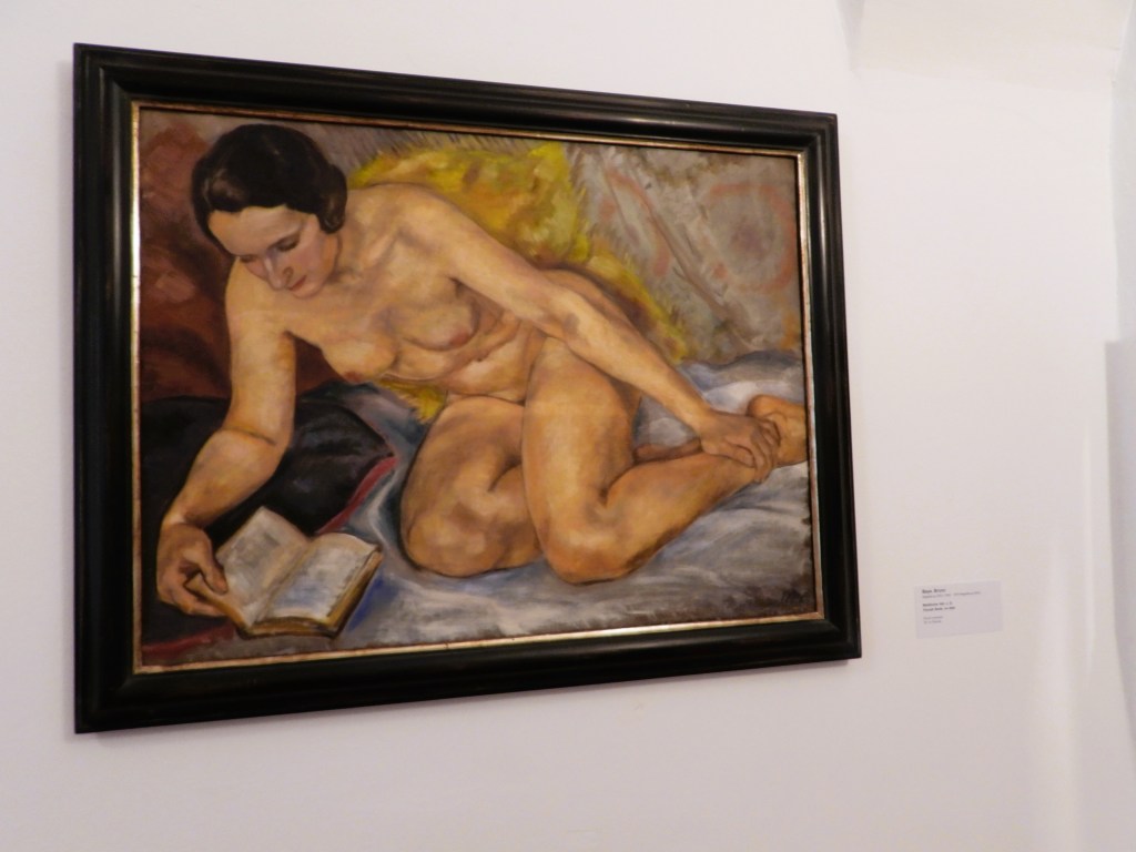 Aktgemälde einer sitzenden Frau, die ein Buch liest, mit sanften Farben und einem dekorativen Hintergrund.