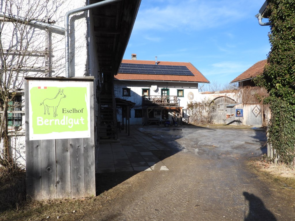 Eingang zum Eselhof Berndlgut mit einem grünen Schild, das einen Esel zeigt, auf einem sonnigen Tag.