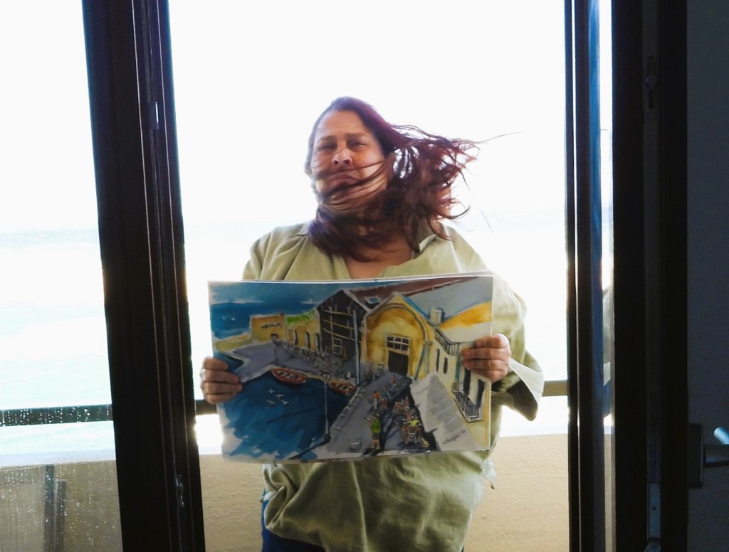 Eine Person mit wehendem Haar steht vor einem Fenster und hält ein gemaltes Bild eines Hafens mit Booten und Gebäuden in der Hand.