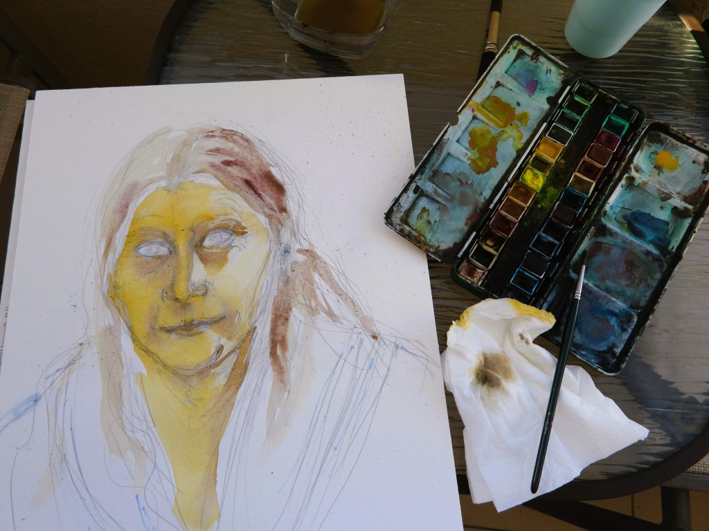 Ein teilweise skizziertes Porträt einer Person mit gelblichen und bräunlichen Wasserfarben, neben einem Farbkasten, einem Pinsel und einem Papiertuch auf einem Tisch.