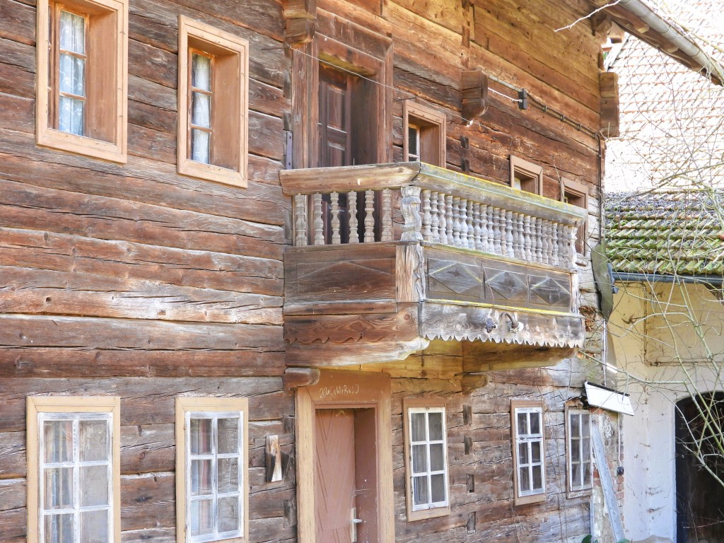 Nahaufnahme eines alten Holzhauses mit einer Holzveranda und Fenstern.